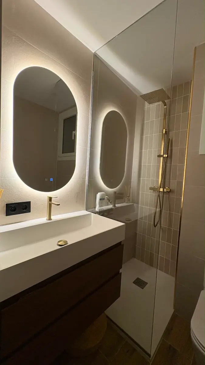 Baño reformado con ducha de obra, mueble suspendido y espejo en Barcelona