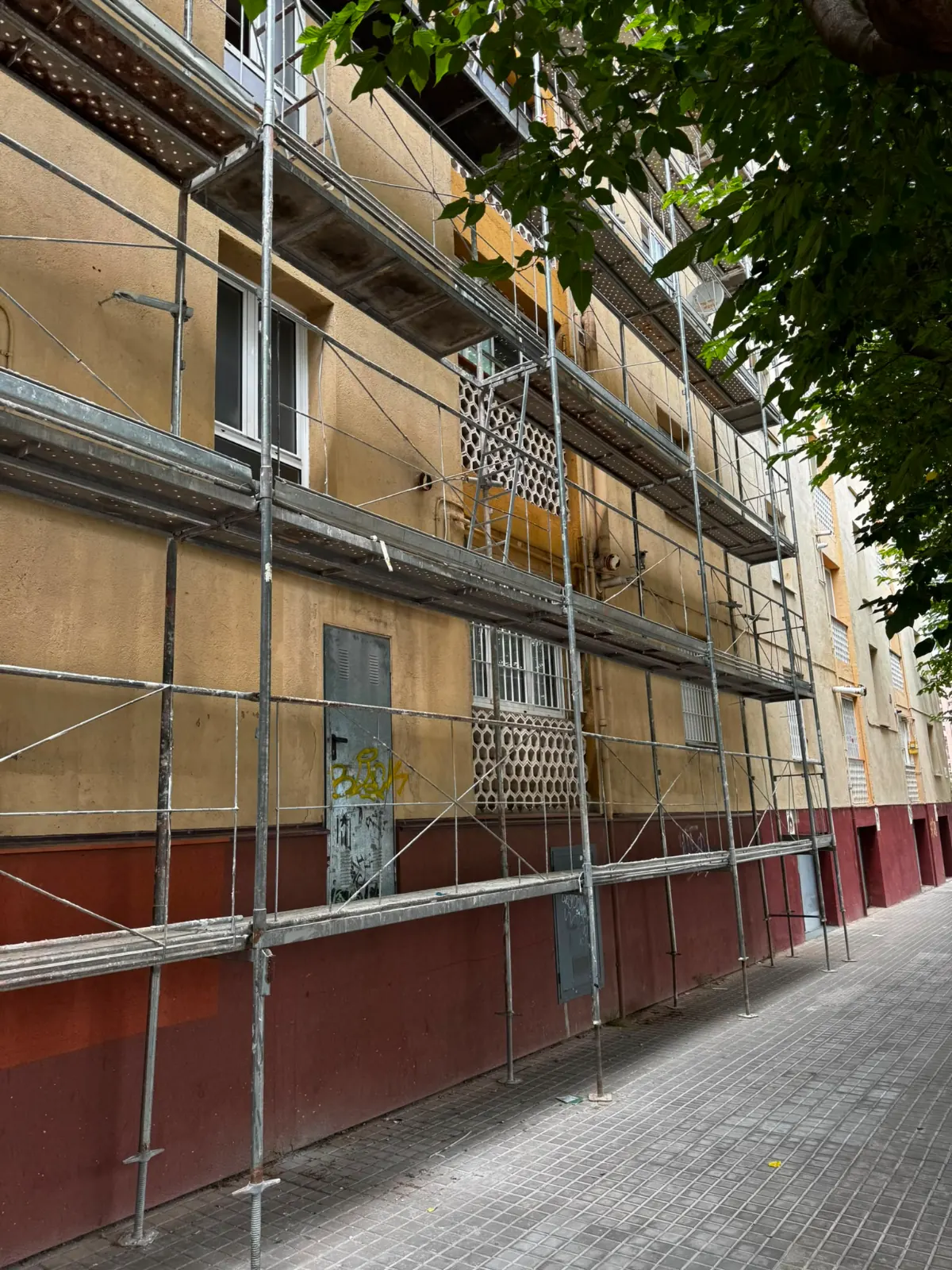 Operario reparando el revoco de una fachada desde un andamio