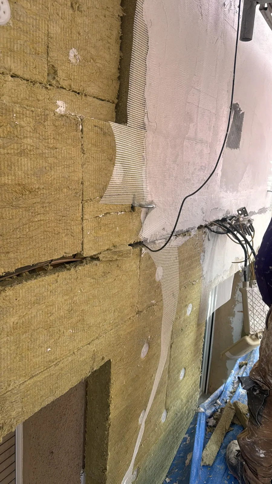 Operarios fijando paneles aislantes de SATE en la fachada de un edificio
