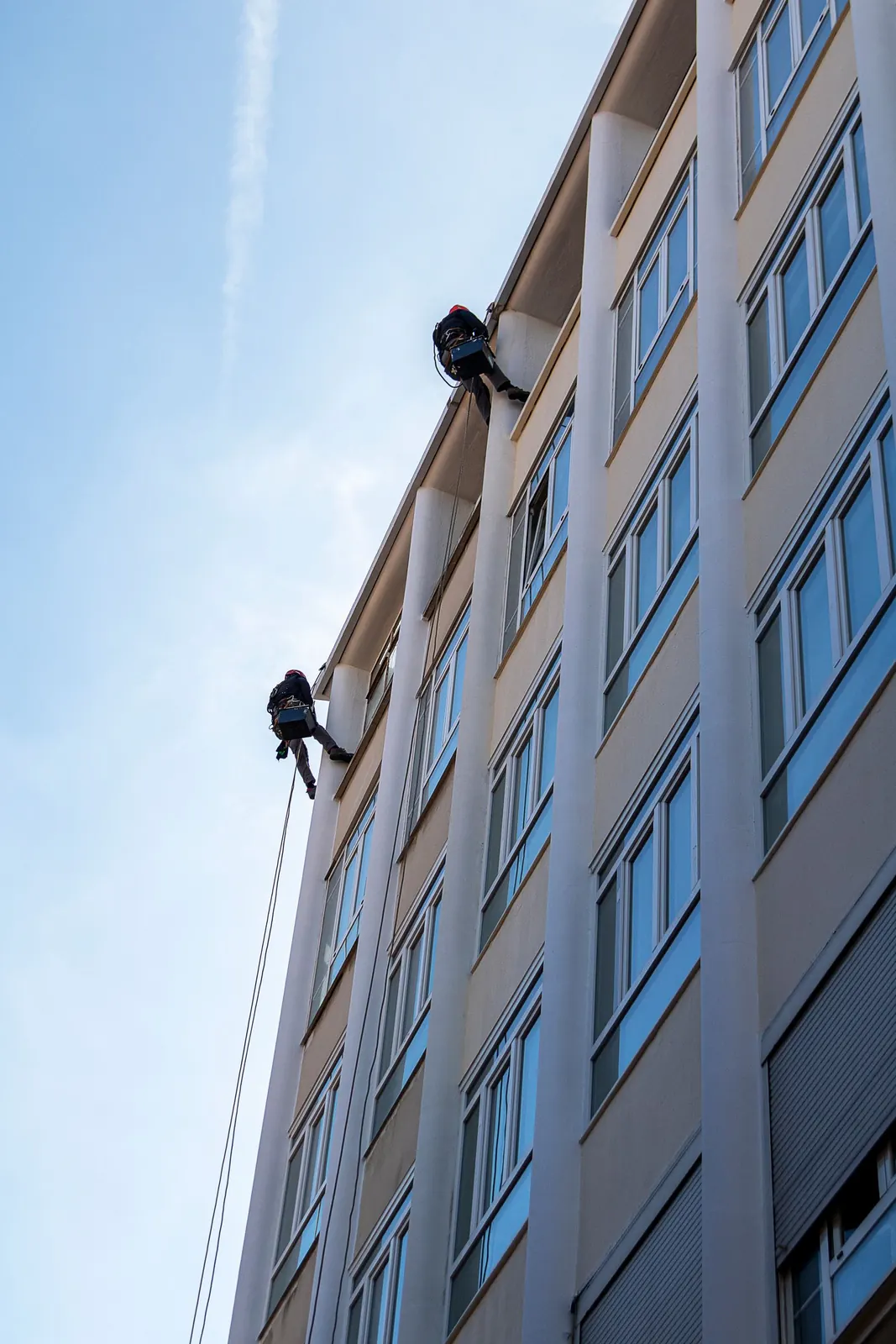 Técnico suspendido reparando una grieta en la fachada de un edificio
