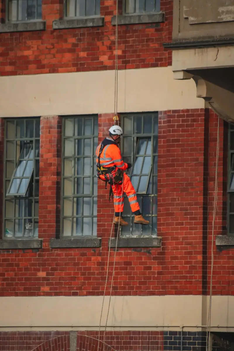 Operario descolgado con cuerdas trabajando en la fachada de un edificio